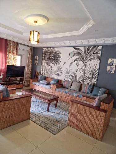 a living room with couches and tables and a mural at Residence Les Bourgeois appartementen. in Yaoundé