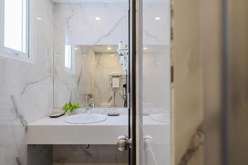 a white bathroom with two sinks and a mirror at TTR Moonstone Apart Hotel in Da Lat