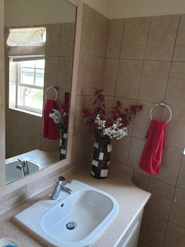 a bathroom with a sink and a vase of flowers at Sweet Home Grenada Caribbean in Lance aux Épines