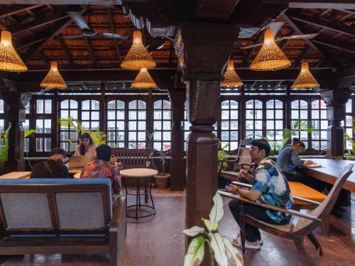 a group of people sitting at tables in a restaurant at Madpackers Goa in Anjuna