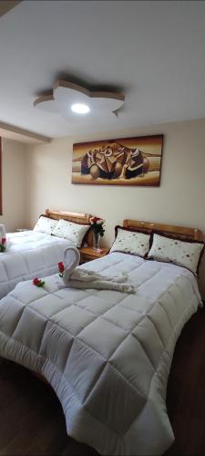 a bedroom with two beds with white blankets at Hospedaje La Joya in Otavalo