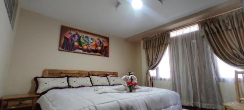 a bedroom with a large white bed with flowers on it at Hospedaje La Joya in Otavalo