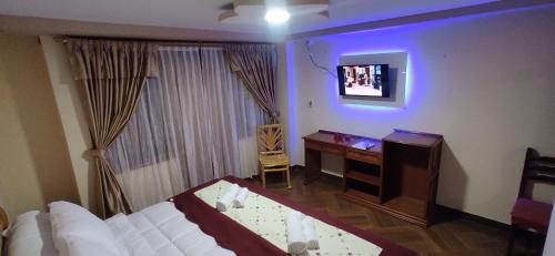 a bedroom with a bed and a desk and a television at Hospedaje La Joya in Otavalo