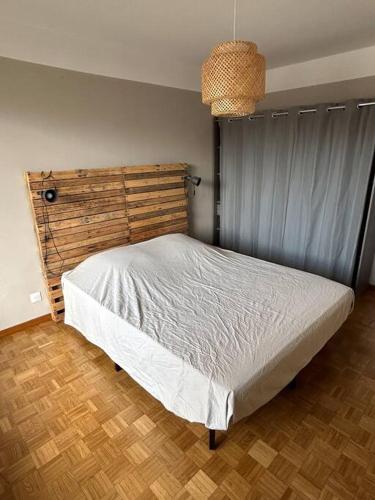 een slaapkamer met een wit bed en een houten hoofdeinde bij Appartement spacieux bien situé in Marseille