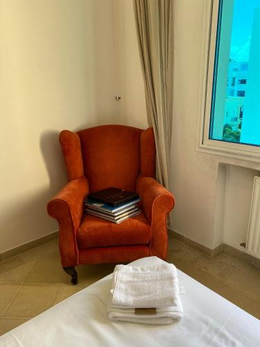a orange chair with a stack of books on it at Lac 2 apartement in Tunis