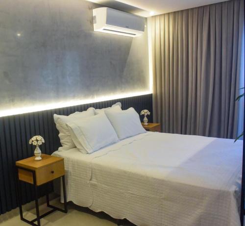 ein Schlafzimmer mit einem großen weißen Bett mit zwei Tischen in der Unterkunft AHA Flat in João Pessoa