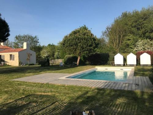 une cour arrière avec une piscine et une maison dans l'établissement Maison vendéenne à 5 min du bord de mer, à Saint-Hilaire-la-Forêt