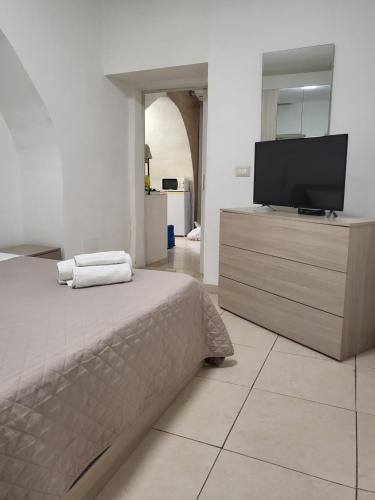 1 dormitorio con 1 cama y vestidor con TV de pantalla plana en Casa Giulia & AL Duomo en Siracusa