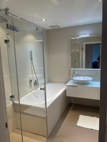 Modernes Apartment an Traumlage in Lugano mit Seesicht في باراديزو: حمام مع دش وحوض استحمام ومغسلة