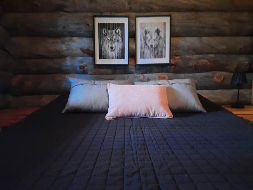 ein Schlafzimmer mit einem Bett mit drei Bildern an der Wand in der Unterkunft Lumi - kelohirsimökki Rukalla, log cabin at Ruka in Kuusamo