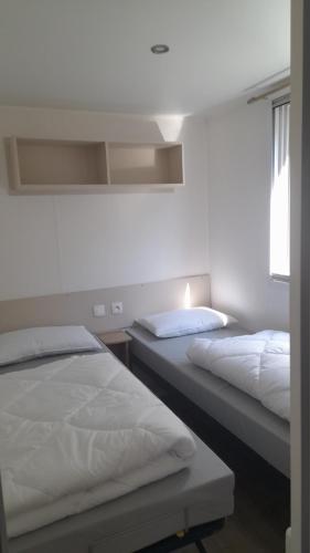 une chambre avec deux lits et une fenêtre dans l'établissement Le Bois Dormant, à Saint-Jean-de-Monts