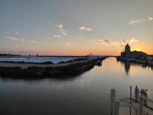 a view of a river with a windmill at sunset at Appartamenti Poseidon in Marsala