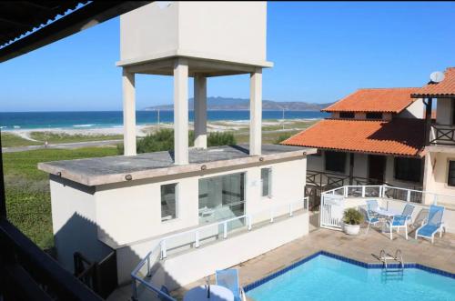 ein Haus mit einem Pool und Meerblick in der Unterkunft Casa familiar pé na areia in Cabo Frio