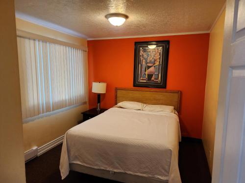 a bedroom with orange walls and a bed and a window at Sunparlor Motel in Leamington