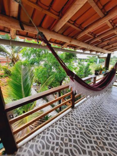 a hammock hanging from a wooden porch with trees at ITAÚNAS Pousada Nossa Palhoça in Itaúnas