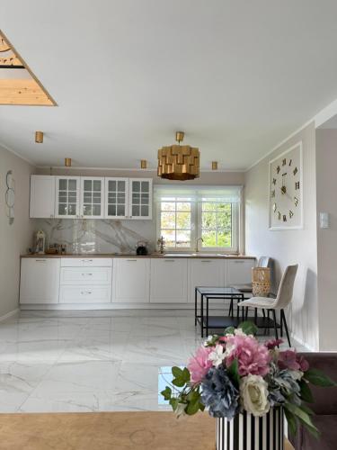 a kitchen with white cabinets and a table with flowers at Jaki tu spokój Domek w Bieszczadach in Wojtkowa