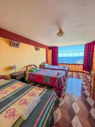 a hotel room with three beds and a large window at Hostal Sol y Lago in Copacabana