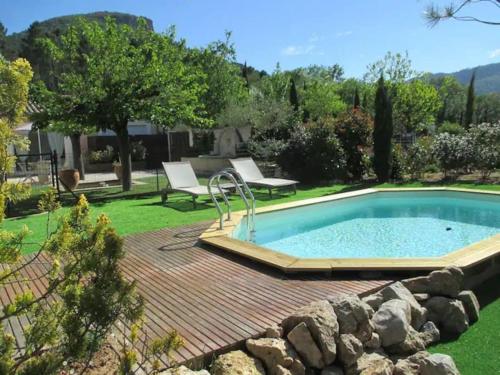 une arrière-cour avec une piscine et une terrasse en bois dans l'établissement Gîte de charme avec piscine privative, à Bagnols-en-Forêt