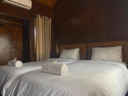 a large white bed with two rolled towels on it at Q'Pelagos Sunset Bungalow in Gili Trawangan