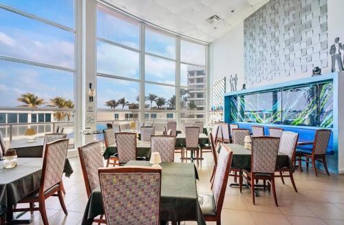 ein Restaurant mit Tischen und Stühlen und großen Fenstern in der Unterkunft Large luxurious direct ocean front Penthouse or Deluxe one bedroom ocean front condo-free parking in Miami Beach