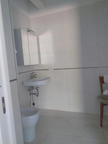 Baño blanco con lavabo y aseo en La casa di Donna Zaira, en Valsinni