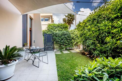een patio met een tafel, stoelen en planten bij In riva al mare in Cagliari