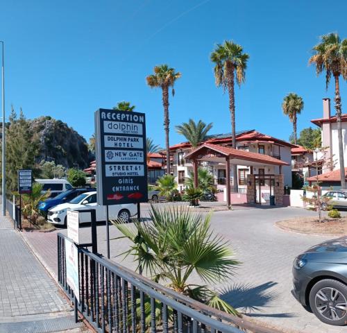 a sign in front of a parking lot with palm trees at Dolphin Apart Hotel in Sarigerme