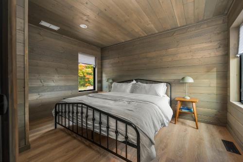 a bedroom with a bed in a wooden wall at Hidden Acres Vestur Cabin in Petoskey