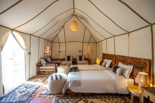 um quarto com 4 camas numa tenda em Golden Camp & Oasis em Merzouga