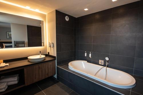 a bathroom with a tub and a sink and a mirror at Best Western Premier Le Chapitre Hotel and Spa in Remiremont
