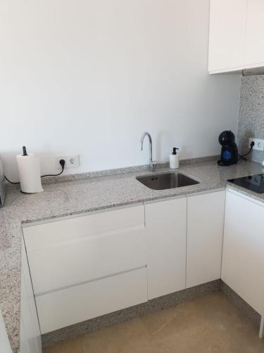 una cucina con mobili bianchi e un lavandino di REYNURBAN a Castillo de Sabinillas