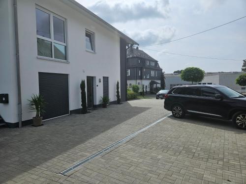 a black car parked in a parking lot next to a house at Haus am Brunnen Wohnung 1 in Klosterkumbd
