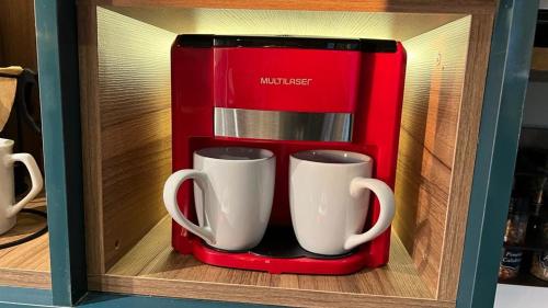 two coffee mugs in a red holder in a drawer at Minicasa Brasileira in Sorocaba