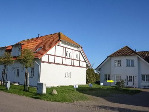um edifício branco com um telhado vermelho ao lado de dois edifícios em Ferienwohnung mit Terrasse am Nationalpark Jasmund em Neddesitz