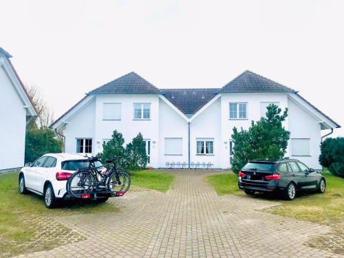 dois carros estacionados em frente a uma casa branca em Ferienwohnung mit Terrasse am Nationalpark Jasmund em Neddesitz