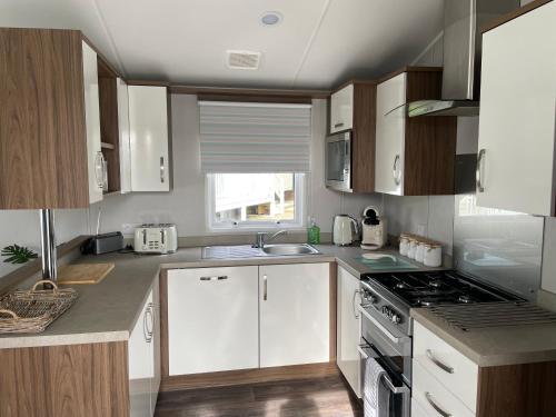 a kitchen with white cabinets and a stove top oven at 6 Berth Comfy Homely Caravan, Dog Friendly in Belton