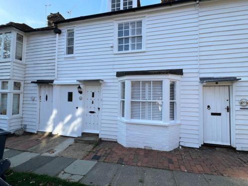 a white house with three doors on a street at The Cottage, 13 Golden Sq. in Kent