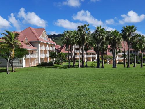 a large building with palm trees in a park at Studio de rêve dans un village de vacances - Salle de bain rénovée 2024 - Clim rénovée 2025 in Sainte-Luce