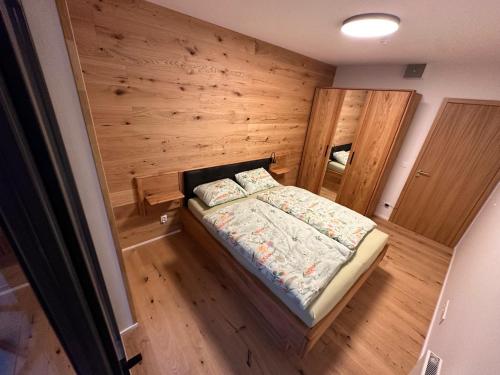 1 dormitorio pequeño con 1 cama en una pared de madera en Apartmán Ski & Bike - Protěž, en Janske Lazne