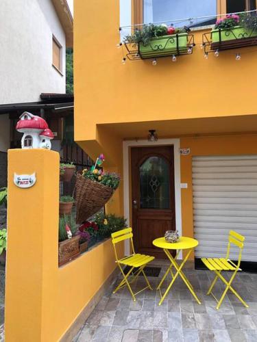 a yellow building with two chairs and a table at Holiday Guesthouse La Casina di Butzi pet friendly - Terme di Arta - Zoncolan in Arta Terme