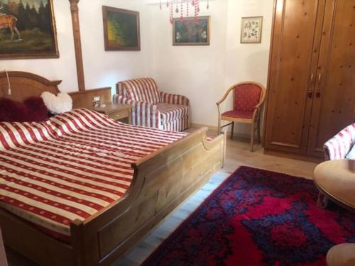 una camera con un grande letto in legno e sedie di La Casina di Butzi: pet friendly ad Arta Terme