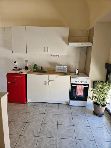 La cuisine est équipée de placards blancs et d'un réfrigérateur rouge. dans l'établissement Casa Gian, à Bénévent