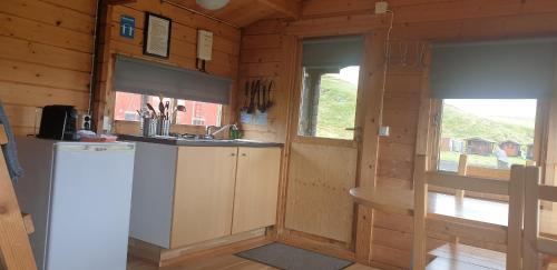 a kitchen with a refrigerator and a sink in a cabin at Hólaskjól Highland Center in Kirkjubæjarklaustur