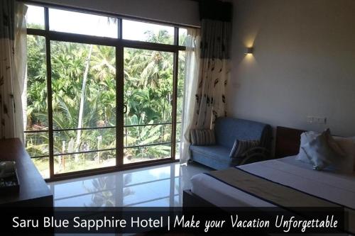 a hotel room with a bed and a large window at Saru Blue Sapphire Hotel in Godakewela