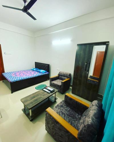 Zimmer mit 3 Betten, einem Sofa und einem Tisch in der Unterkunft Ashirwad Homestay in Dibrugarh