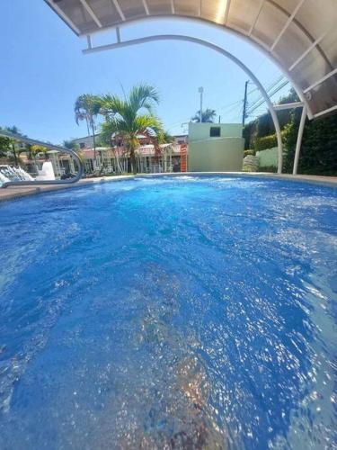 a large pool of blue water with an umbrella at Casa Mora in Jacó