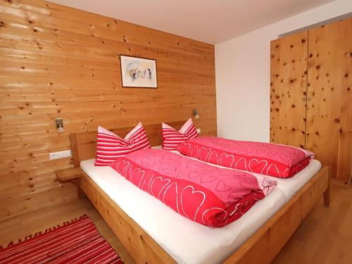 1 dormitorio con 2 camas y almohadas rojas en Kometer App Enzian, en Fendels