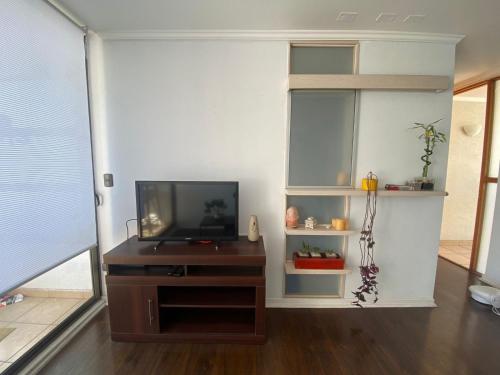 een woonkamer met een televisie op een houten entertainmentcentrum bij Departamento full equipado, 3 dormitorios in La Serena