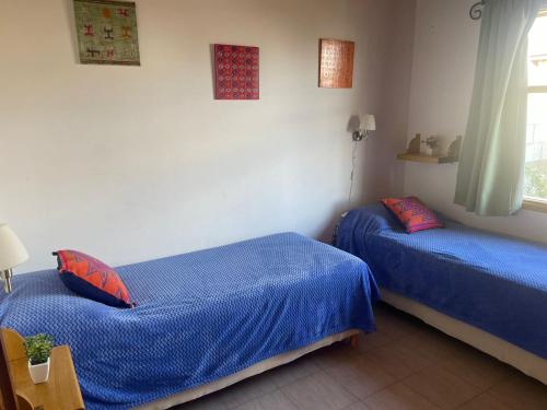 two beds in a room with blue sheets at El Abrigo in El Calafate