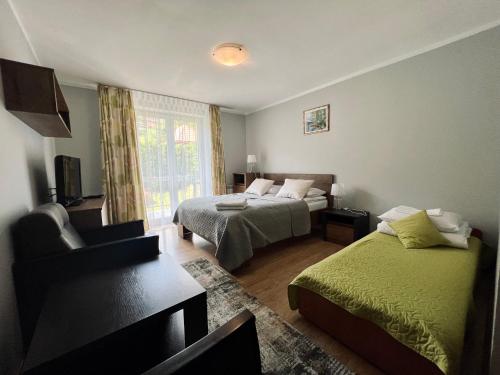 a bedroom with two beds and a couch and a window at Noclegi Solina Sunrise in Solina